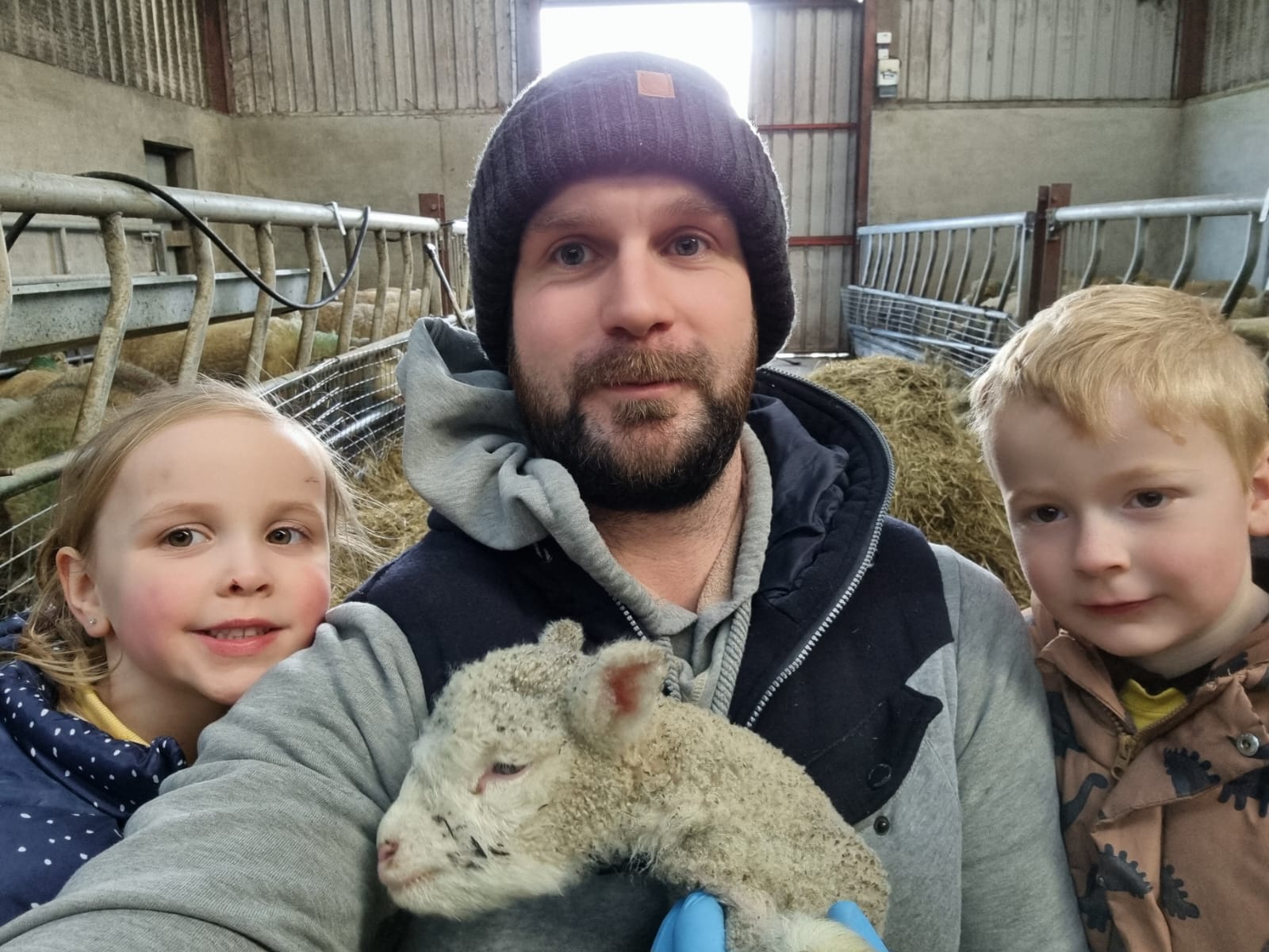 Sheep farmer with lamb and children